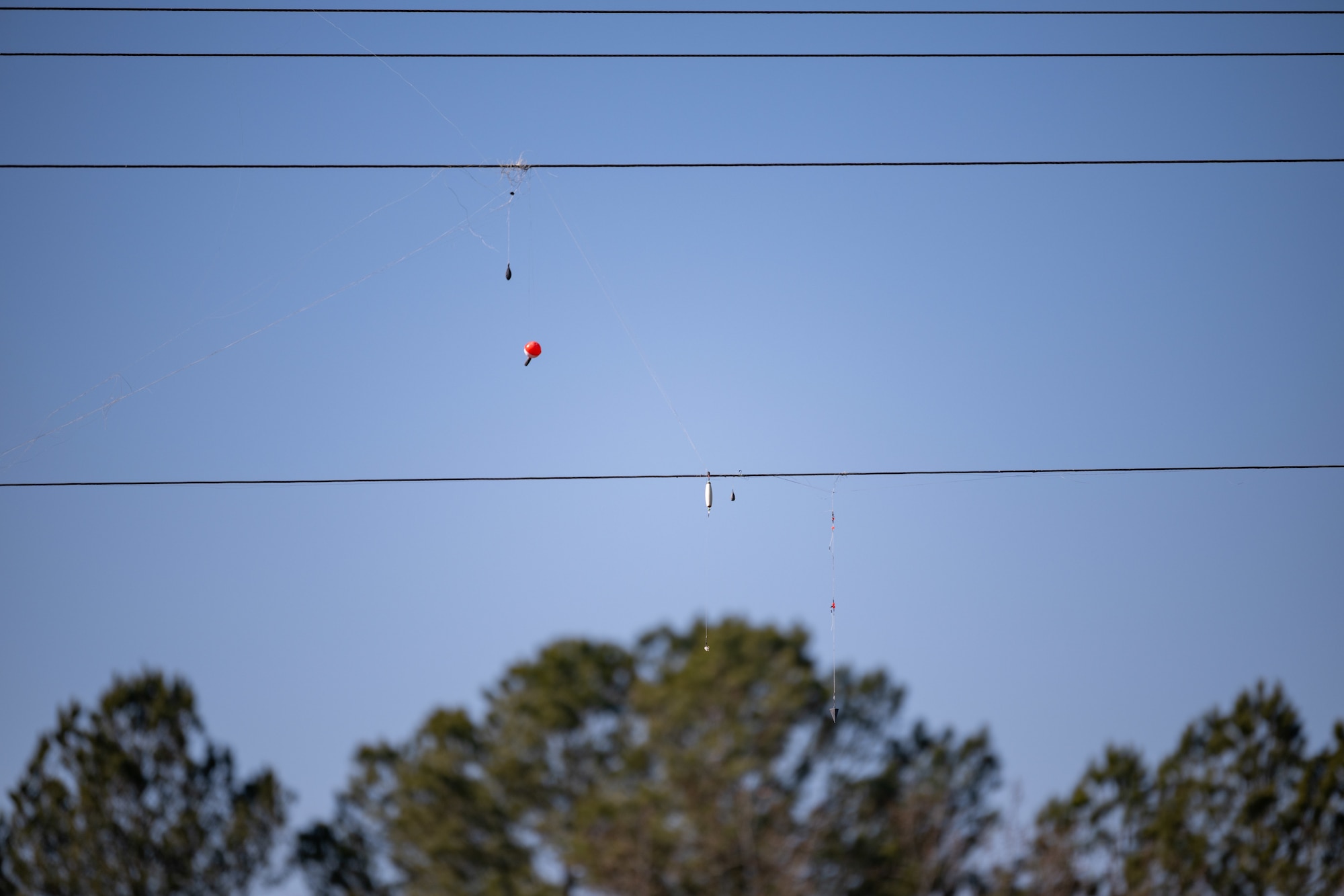 Fishing line hangs from utility lines crossing the Elk River at the Elk River Dam on Arnold Air Force Base, Tenn. Jan. 28, 2025. Work is set to soon begin to prevent public access to the dam structure through the installation of security fencing around the downstream training walls. The effort is to ensure property security and safety in the area. The river will still be accessible to recreationalists for fishing and other activities. (U.S. Air Force photo by Keith Thornburgh)