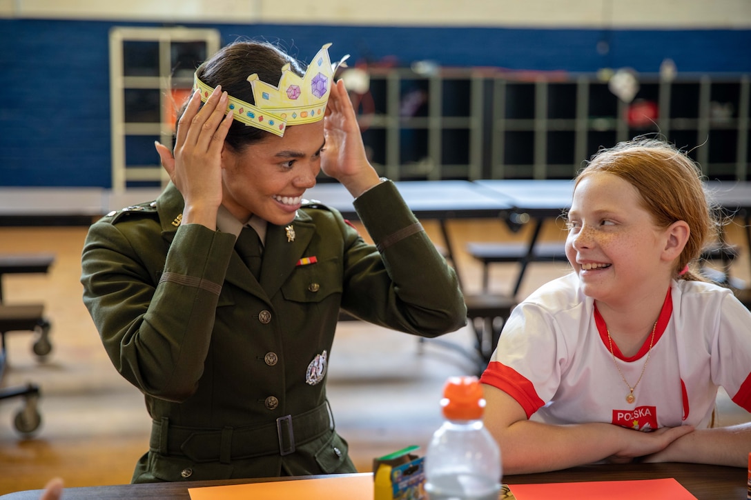 A soldier wearing a paper crown sits next to a smiling child.