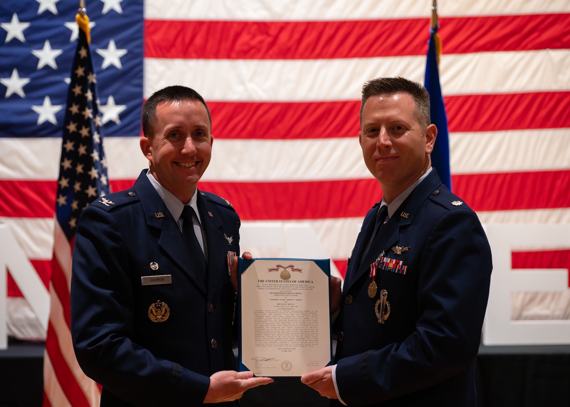 U.S. Air Force Lt. Col. Anthony Santino, 576th Flight Test Squadron commander, right, receives a citation for a meritorious service medal from U.S. Air Force Col. Dustin Harmon, 377th Test and Evaluation Group commander during the 576 FLTS change of command ceremony at Vandenberg Space Force Base, Calif., June 17, 2025. Santino was awarded the meritorious service medal for his accomplishments as the commander of the 576 FLTS.