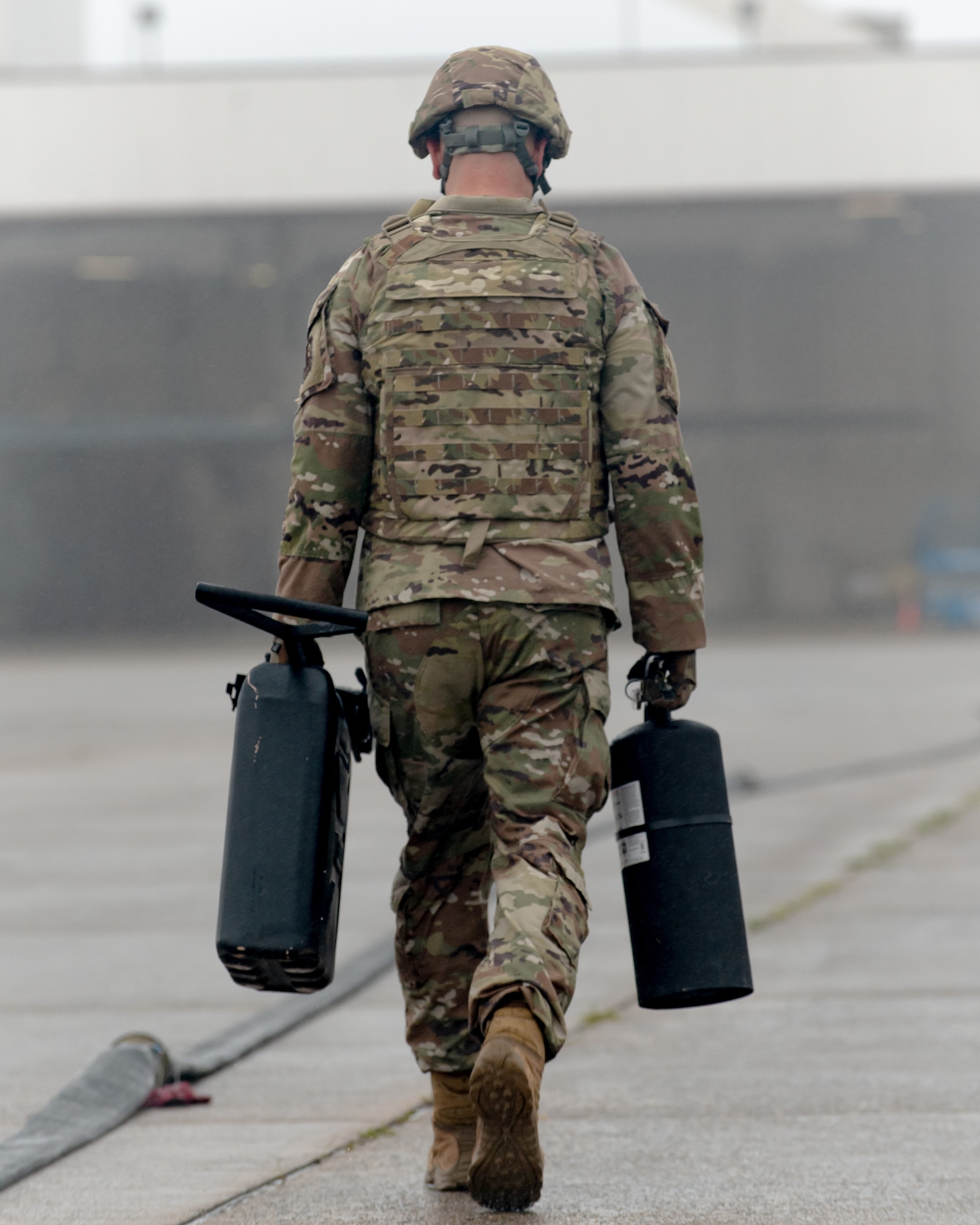 A special operations Airman here carries a five-gallon water bucket and fire extinguisher during a Forward Arming and Refueling Point tryout at the 193rd Special Operations Wing June 17, 2025.
