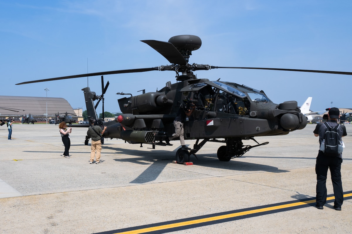Media members capture footage of an AH-64 Apache helicopter during a media engagement.