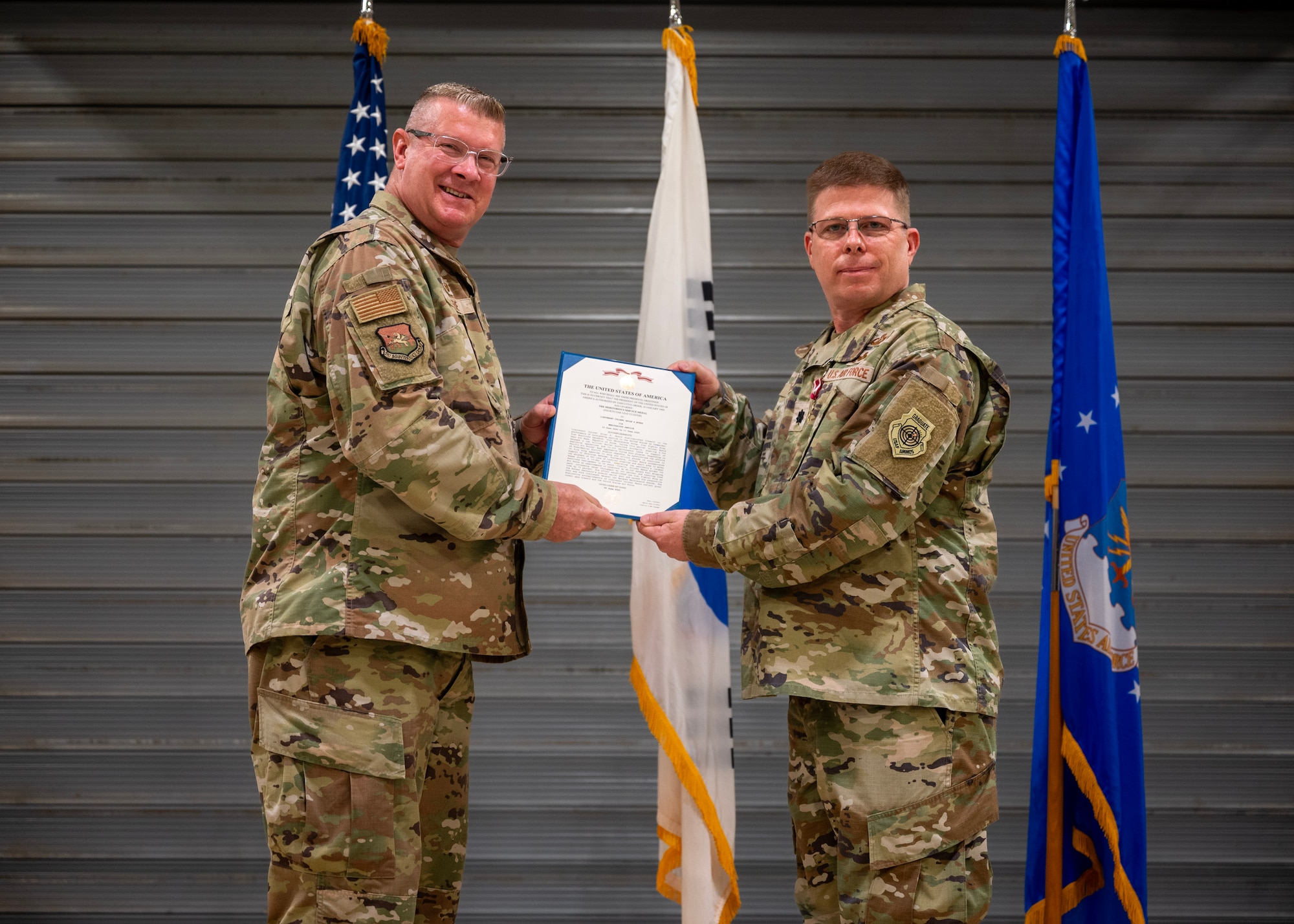 U.S. Air Force Lt. Col. Brian Myers, outgoing 51st Munitions Squadron commander, right, receives the Meritorious Service Medal from Col. Kenneth Beebe, 51st Maintenance Group commander, left, during a Change of Command ceremony at Osan Air Base, Republic of Korea, June 17, 2025. Myers led more than 310 Airmen and 12 Korean professionals in rapidly generating lethal air power. (U.S. Air Force photo by Staff Sgt. Sarah Williams)