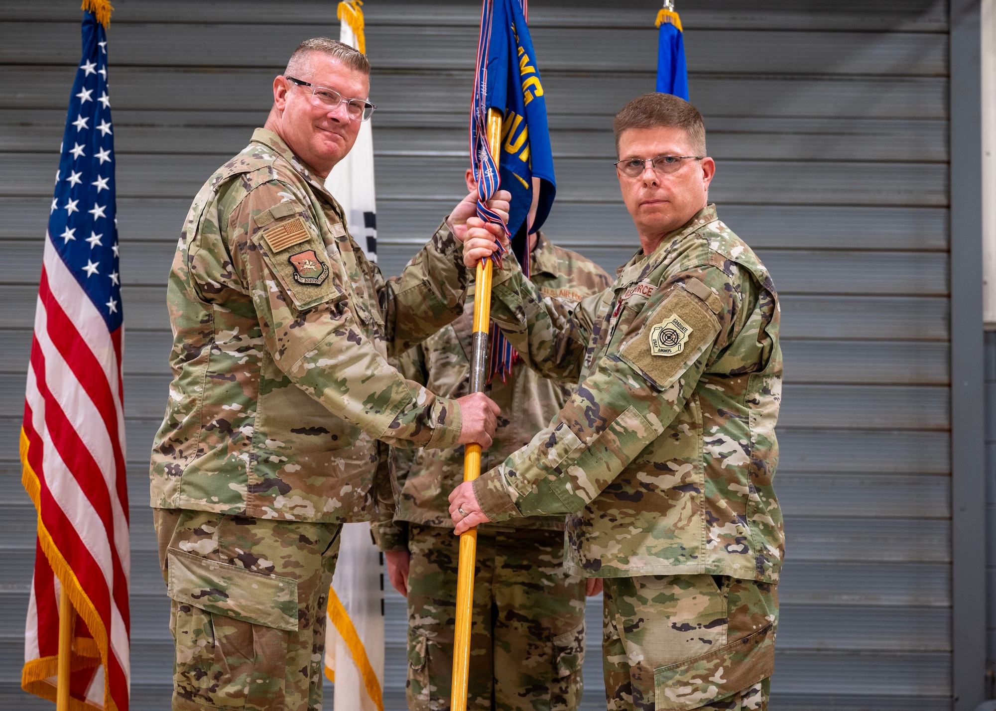 U.S. Air Force Col. Kenneth Beebe, 51st Maintenance Group commander, left, receives the guidon from Lt. Col. Brian Myers, outgoing 51st Munitions Squadron commander, right, during a Change of Command ceremony at Osan Air Base, Republic of Korea, June 17, 2025. Myers led over 310 Airmen and 12 Korean professionals in rapidly generating lethal air power to “Take the Fight North”. (U.S. Air Force photo by Staff Sgt. Sarah Williams)