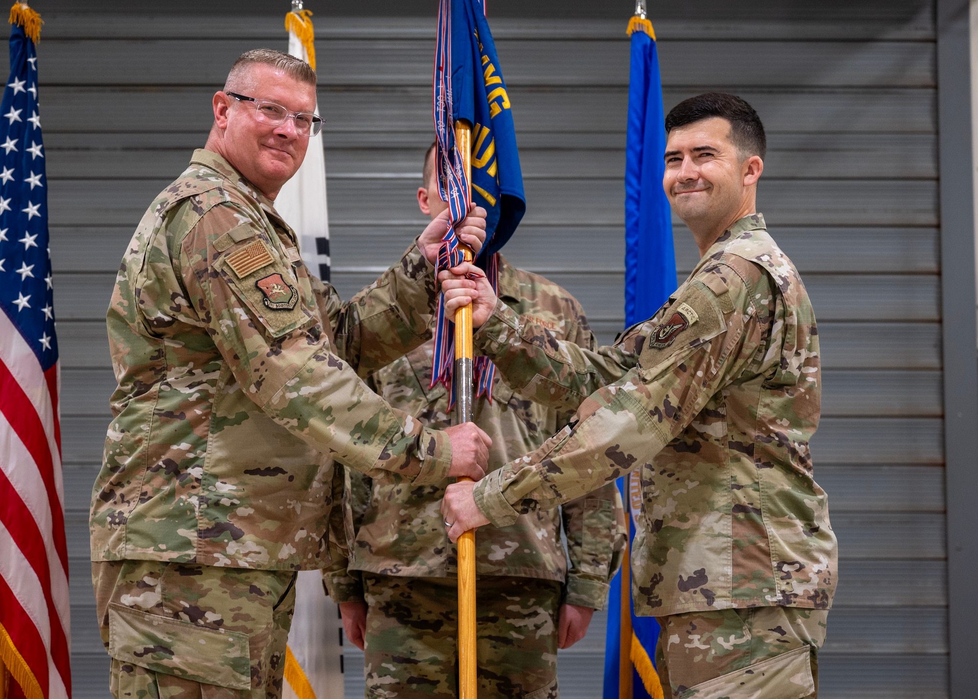 U.S. Air Force Col. Kenneth Beebe, 51st Maintenance Group commander, left, passes the guidon to Maj. James Phillips, incoming 51st Munitions Squadron commander, right, during a Change of Command ceremony at Osan Air Base, Republic of Korea, June 17, 2025. Prior to assuming command, Phillips led the 4th Munitions Squadron as the commander at Seymour Johnson Air Force Base, North Carolina. (U.S. Air Force photo by Staff Sgt. Sarah Williams)