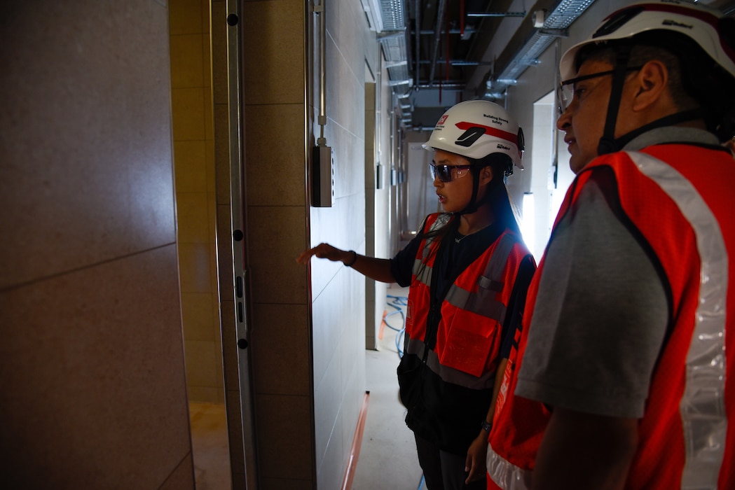 two people in hardhats inspecting a dog kennel
