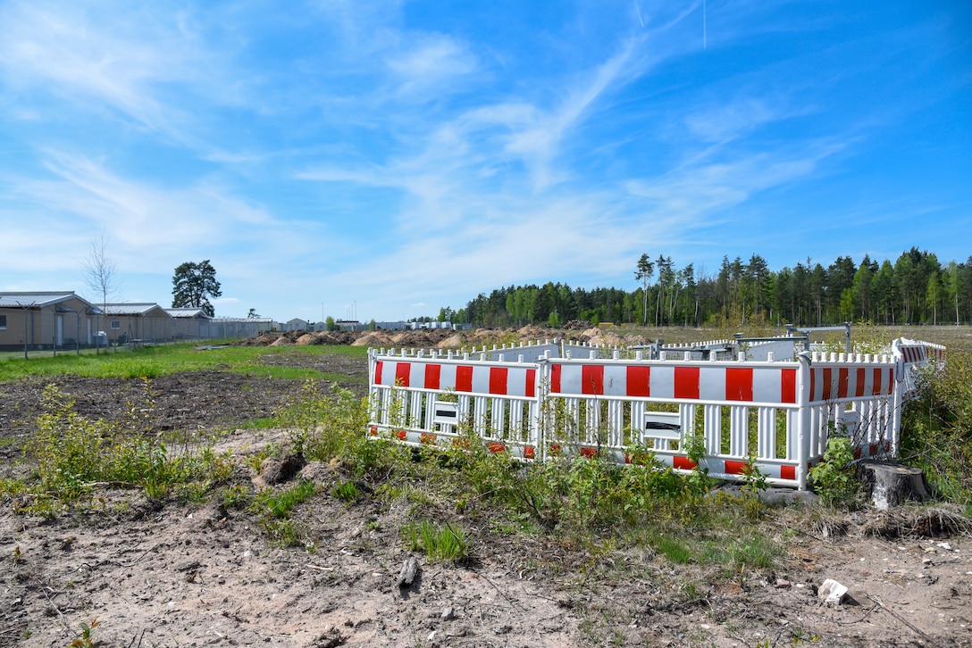 Area of torn up ground. To one side is a section of hazard fencing