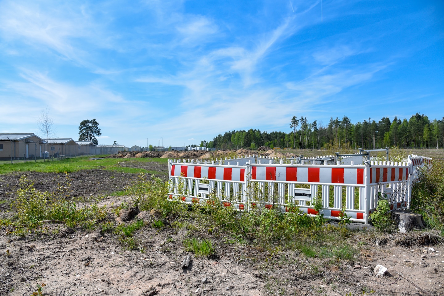 Area of torn up ground. To one side is a section of hazard fencing