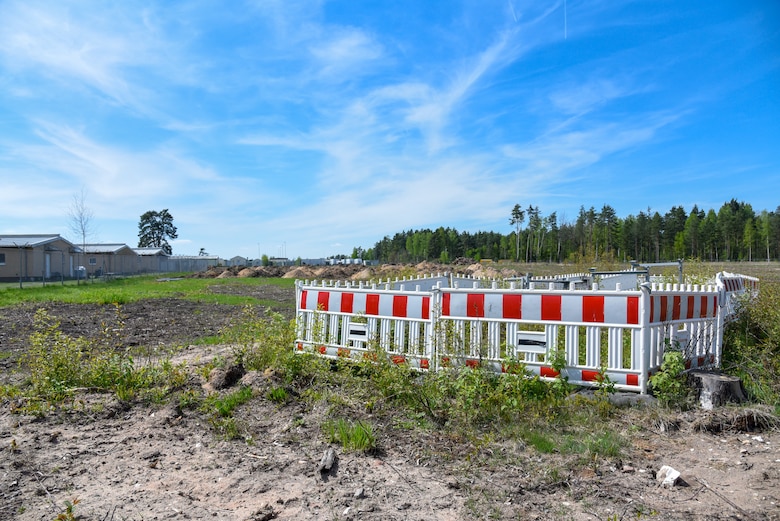 Area of torn up ground. To one side is a section of hazard fencing