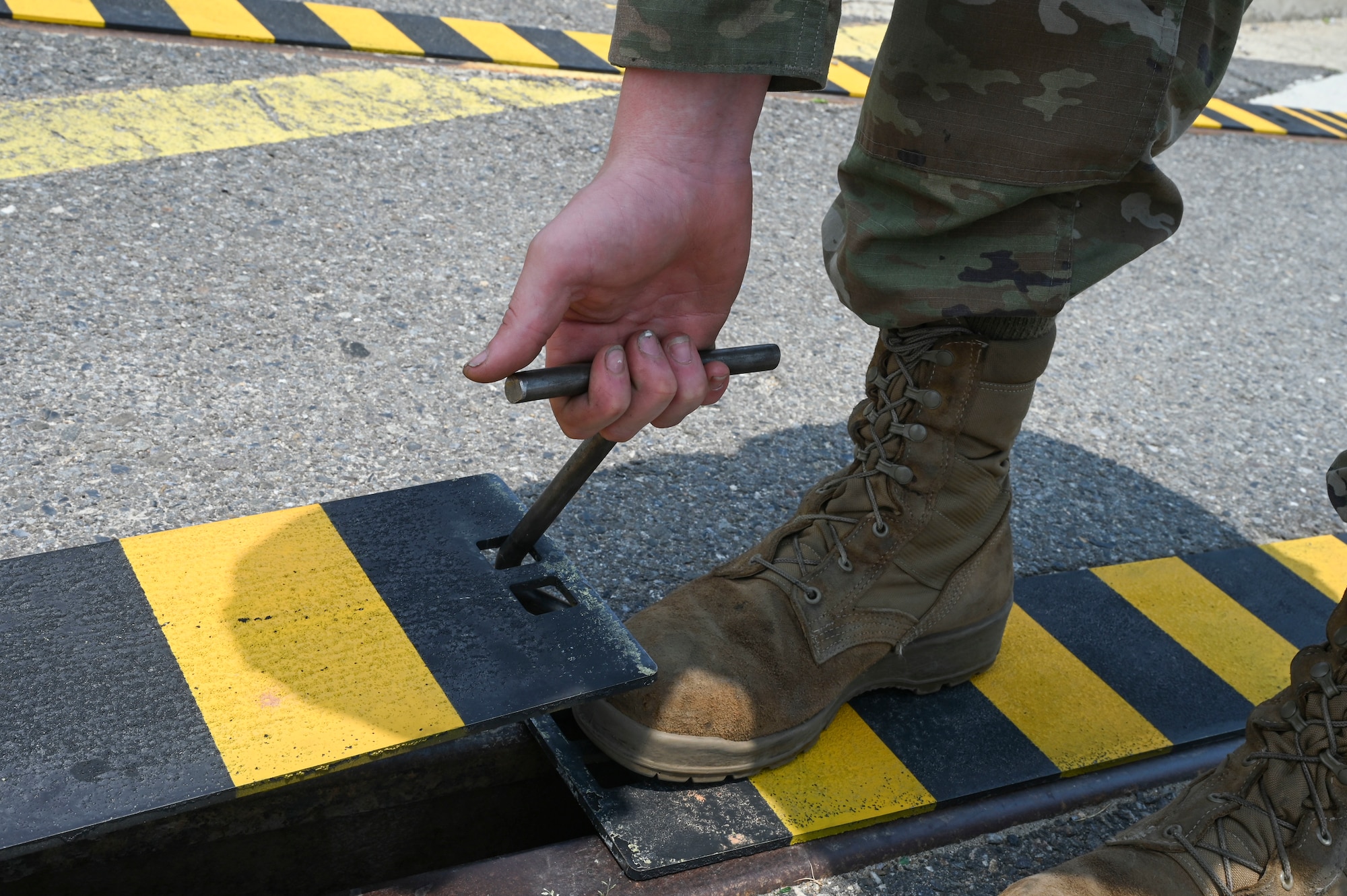 Airman 1st Class Dominic Varoz, 8th Maintenance Squadron aircraft metals technology journeyman, uses a specially fabricated hook to lift a custom built railroad track cover at Kunsan Air Base, Republic of Korea, June 17, 2025.