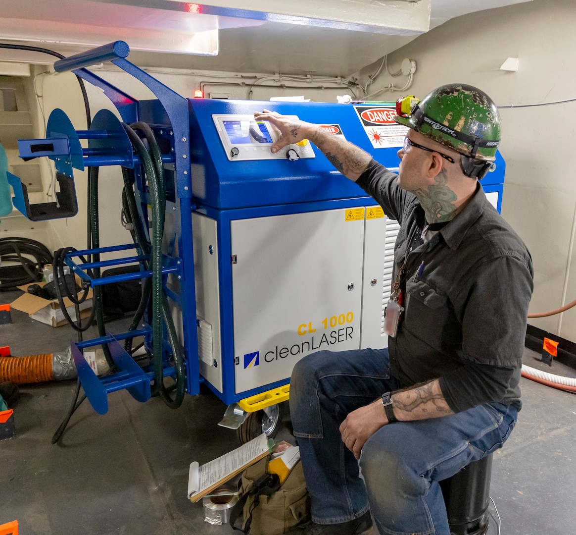 Chase Absher, painter, Shop 71, Painters, Blasters, Tilesetters, adjusts the settings and parameters on the Adapt Laser CL 1000 machine, which is used to power the laser ablation tool, May 22, 2025, while working aboard USS Ronald Reagan (CVN 76), at Puget Sound Naval Shipyard & Intermediate Maintenance Facility in Bremerton, Washington. (U.S. Navy photo by Wendy Hallmark)