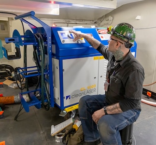 Chase Absher, painter, Shop 71, Painters, Blasters, Tilesetters, adjusts the settings and parameters on the Adapt Laser CL 1000 machine, which is used to power the laser ablation tool, May 22, 2025, while working aboard USS Ronald Reagan (CVN 76), at Puget Sound Naval Shipyard & Intermediate Maintenance Facility in Bremerton, Washington. (U.S. Navy photo by Wendy Hallmark)