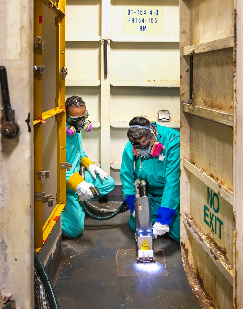 Ladante Taylor, supervisor, and Elizabeth Adapon, painter, Shop 71, Painters, Blasters, Tilesetters, use a laser ablation tool to remove paint coating and corrosion aboard USS Ronald Reagan (CVN 76), May 22, 2025, at Puget Sound Naval Shipyard & Intermediate Maintenance Facility in Bremerton, Washington. (U.S. Navy photo by Wendy Hallmark)