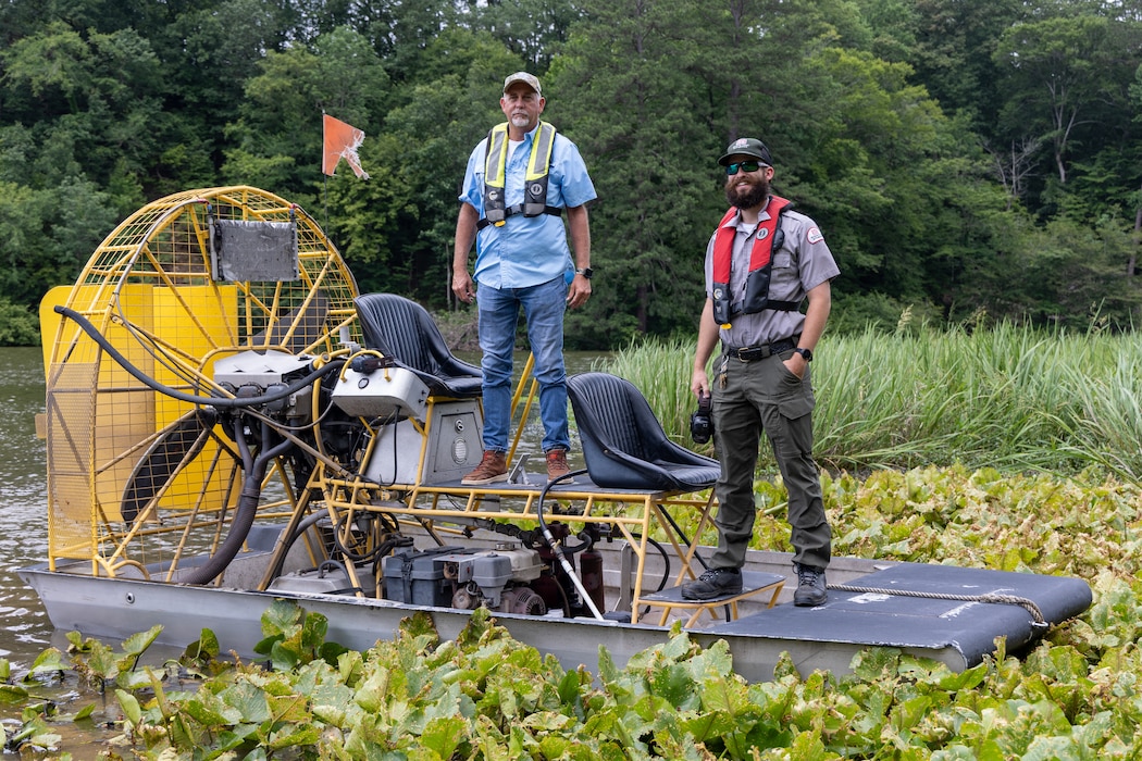 Two men standing on an airboat.