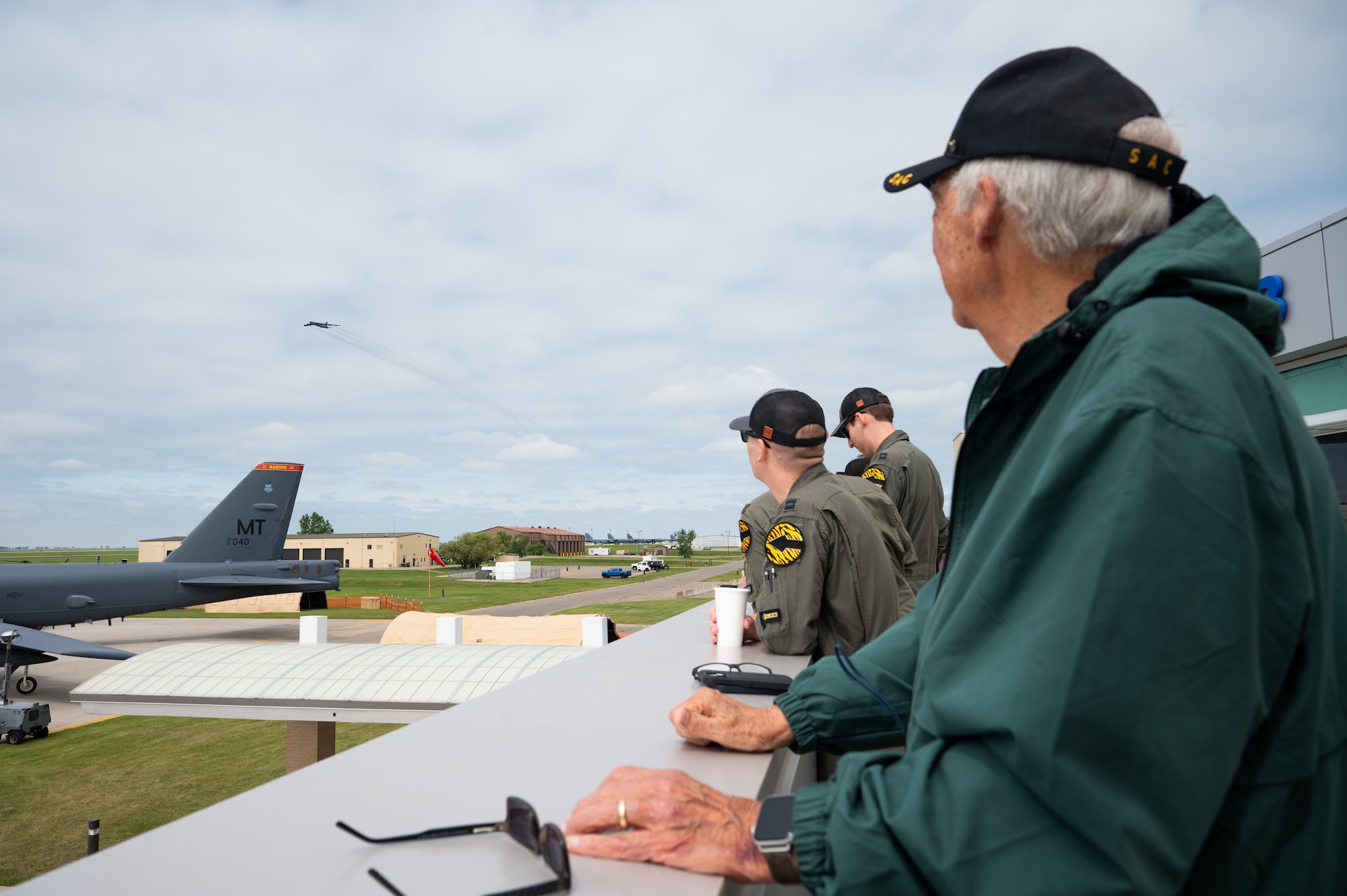 Gary Lee and Airmen watch a B-52H Stratofortress flying overhead in the distance.