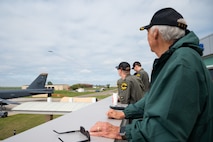 Gary Lee and Airmen watch a B-52H Stratofortress flying overhead in the distance.