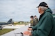 Gary Lee and Airmen watch a B-52H Stratofortress flying overhead in the distance.