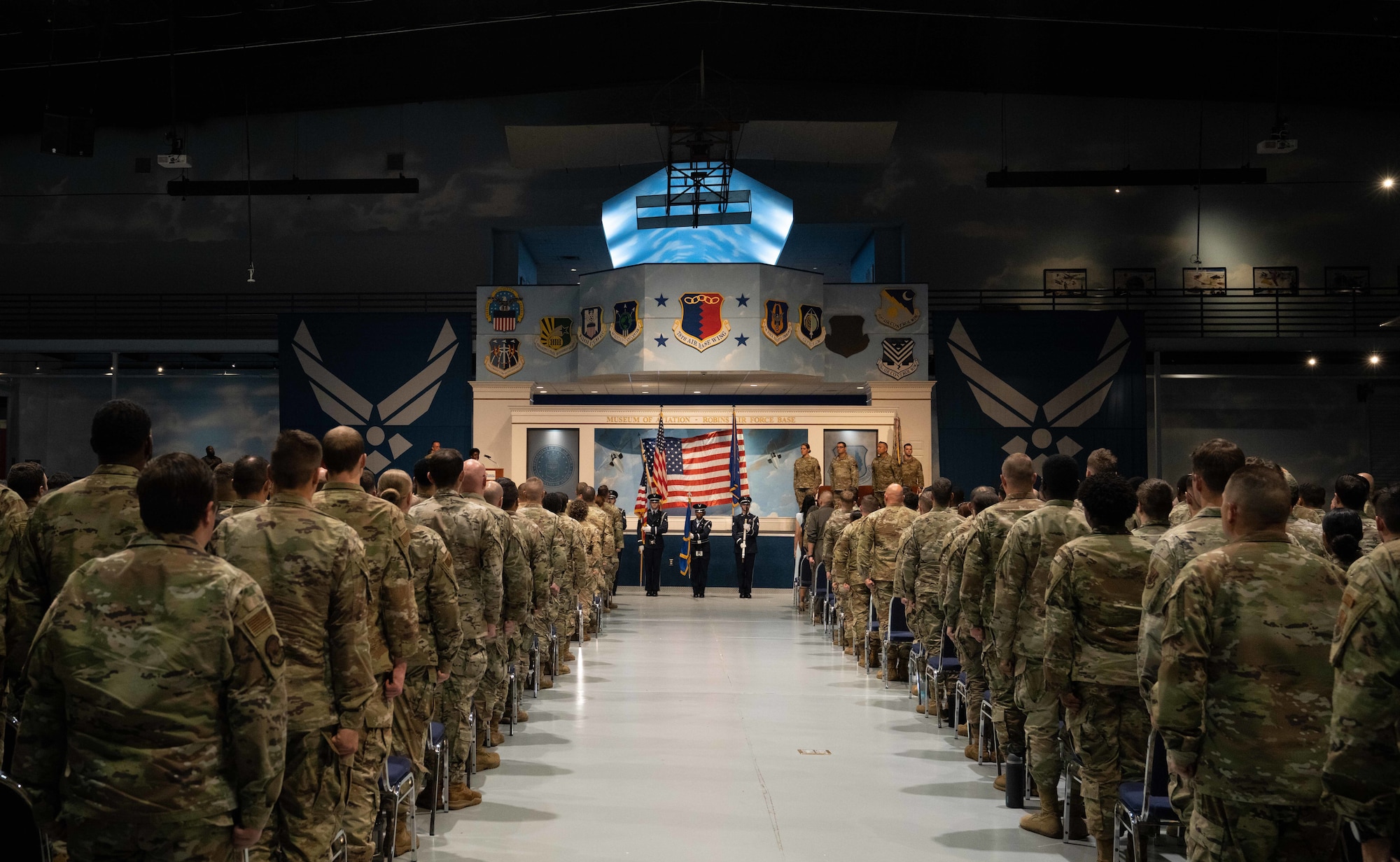 A group of military personnel standing while looking toward a stage
