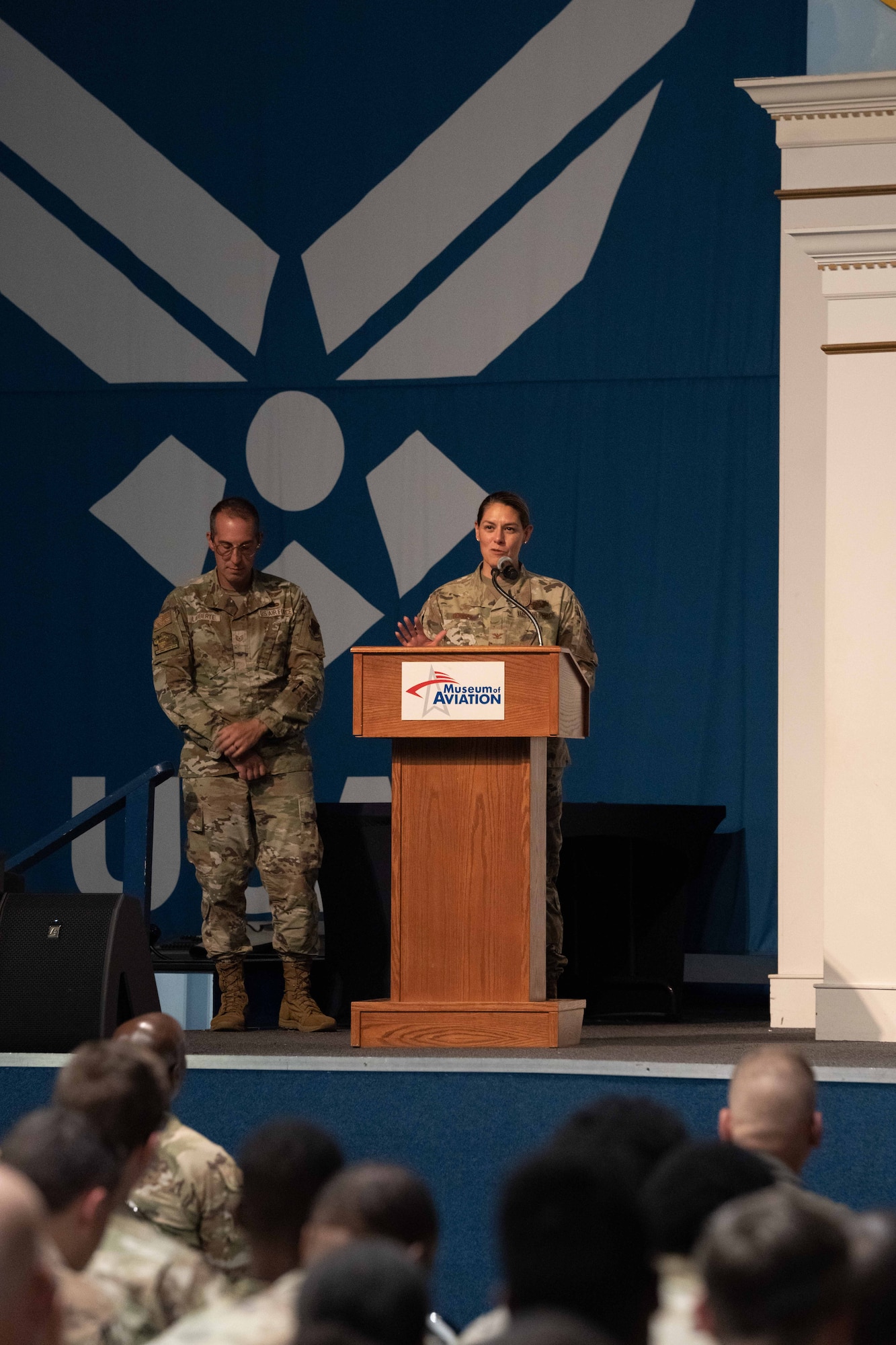 Woman in military uniform standing behind a podium while speaking