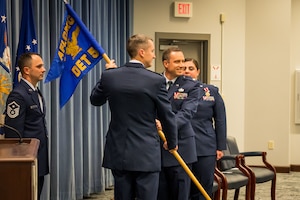 Col. Chadwick Steipp, Deputy Commander, AFLCMC, passes the Detachment 5 guidon to Maj. Austin Myers, symbolizing Myers’ official assumption of