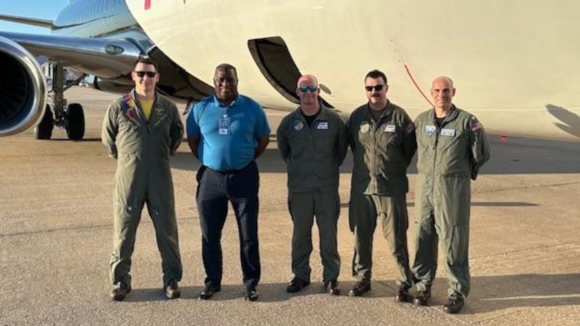 5 men standing in front of plane.
