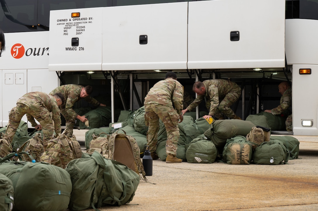 Soldiers assigned to the 1st Infantry Division remove stowed luggage from a bus.