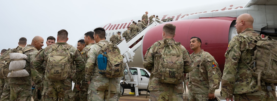 Soldiers assigned to the 1st Armored Division board an aircraft.