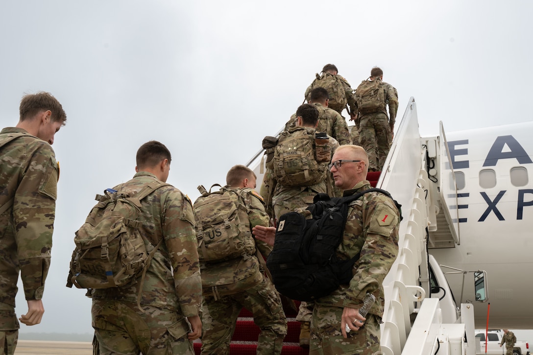 Soldiers assigned to the 1st Infantry Division board an aircraft.