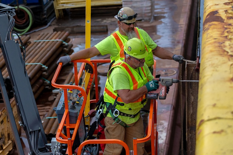 Construction crews work at a navigational lock along a river.