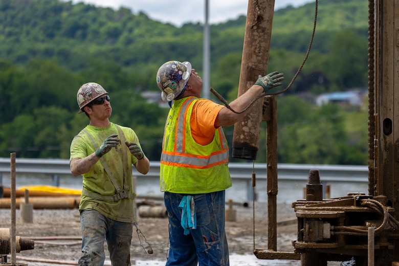 Construction workers make groundbreaking progress at a construction site at a navigational lock along a river.