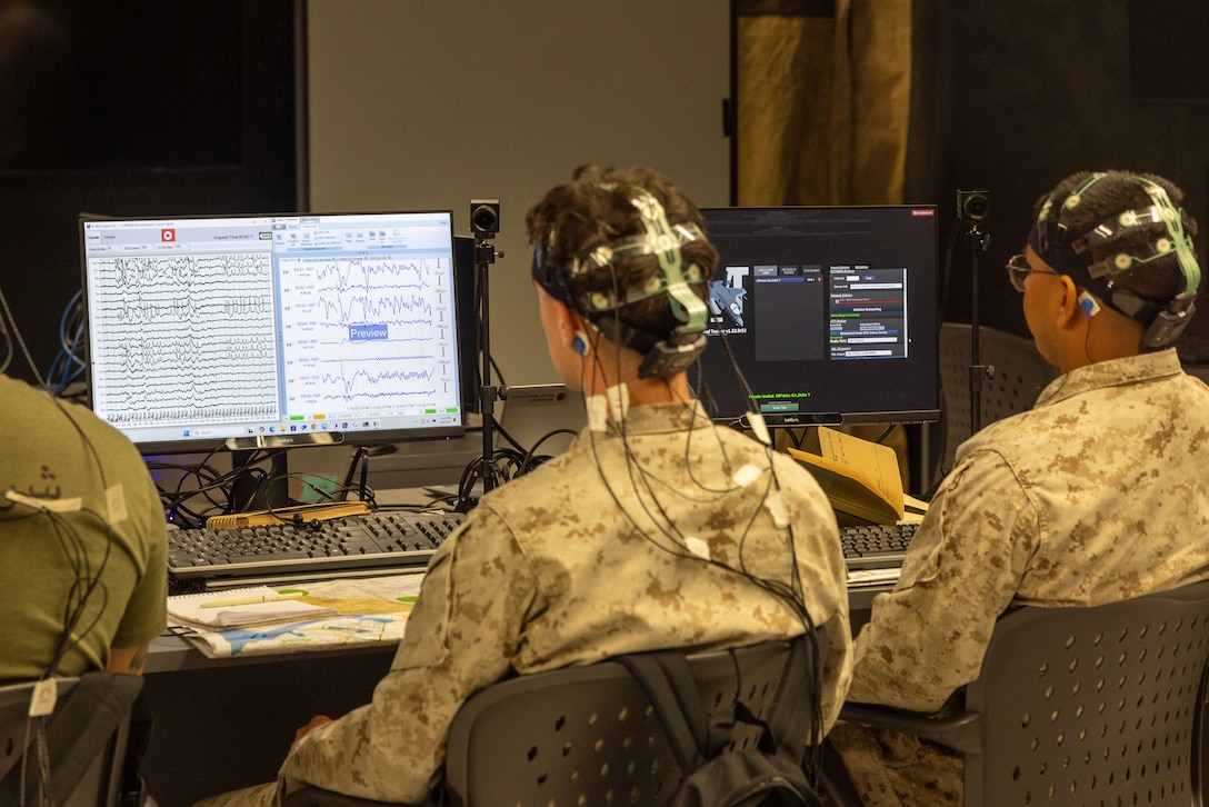 U.S. Marine Corps Lance Cpl. Harrison Murphy, a South Carolina native, left, and Lance Cpl. Felix Cruzdiaz, a Texas Native, both infantry Marines with 3rd Light Armored Reconnaissance Battalion, 1st Marine Division, I Marine Expeditionary Force, monitor their brain activity during training at the Battle Simulation Center, Marine Corps Air Ground Combat Center, Twentynine Palms, California, April 8, 2025. The Defense Advanced Research Project Agency’s partnership with MAGTFTC’s BSC and 1st MARDIV units represents a long-term investment in gaining a strategic edge by developing performance metrics for Fire Support Team training and enhancing systems like the  Joint Terminal Attack Controller Virtual Trainer. (U.S. Marine Corps photo by Cpl. Anna Higman)