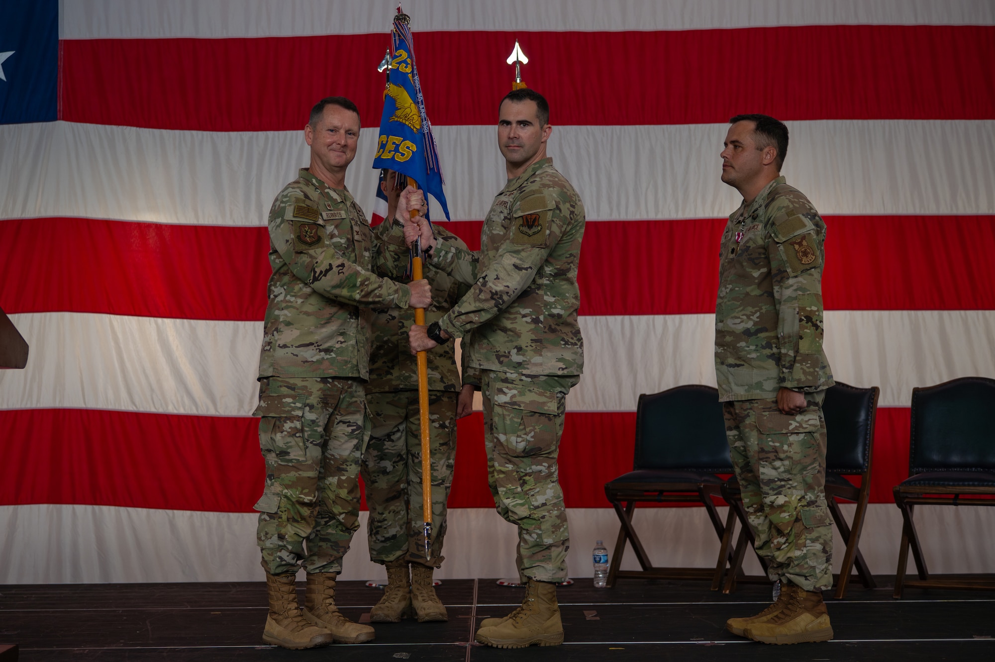 Men stand on stage as they pass a guidon.