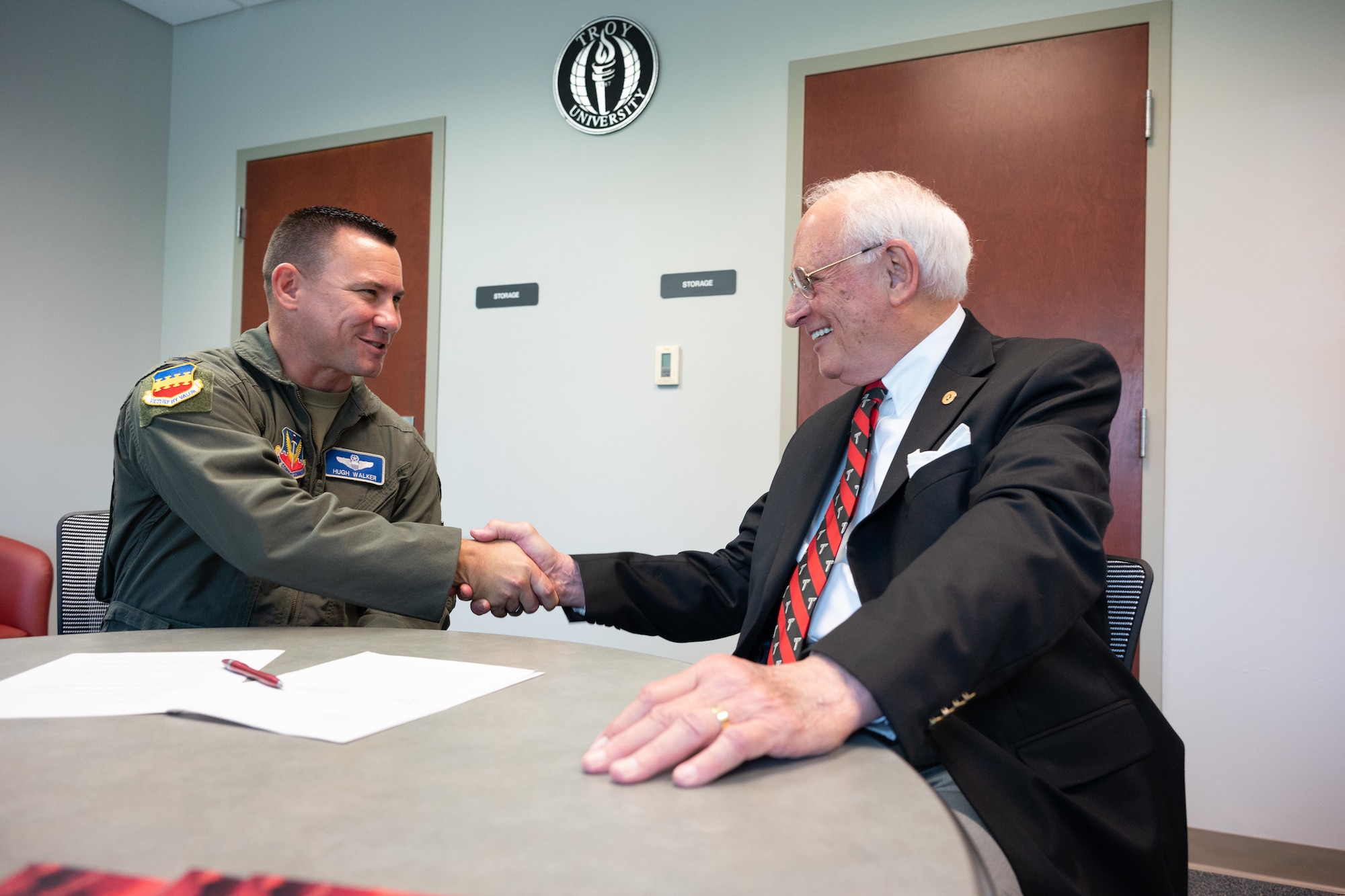 U.S. Air Force Col. Hugh Walker, 20th Fighter Wing deputy commander and acting wing commander, shakes hands with Troy University chancellor Dr. Jack Hawkins, Jr., during a ceremonial partnership agreement signing at Shaw Air Force Base, S.C., June 17, 2025.