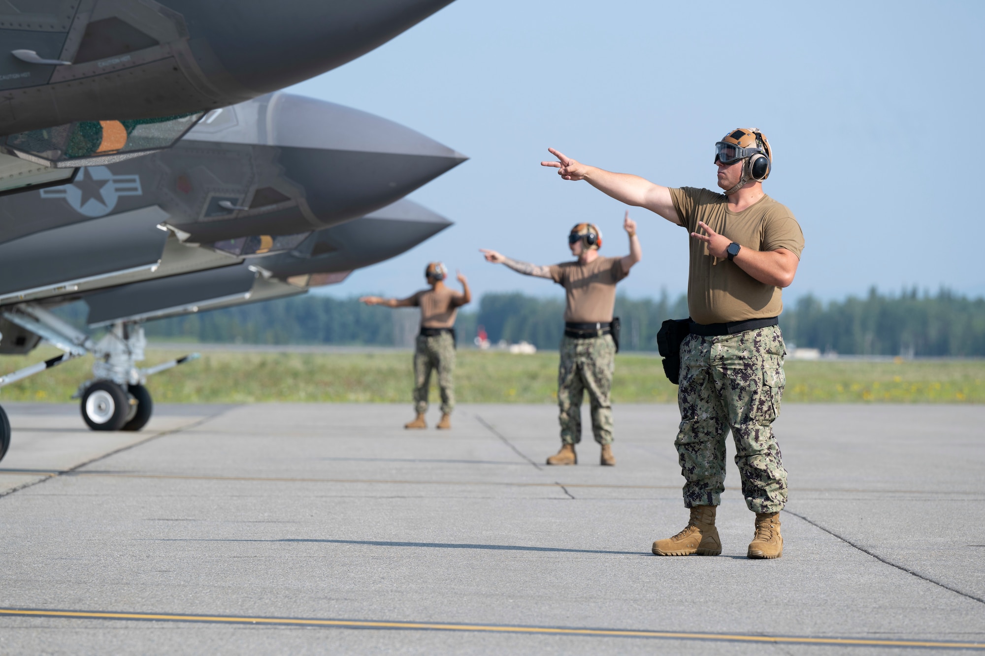U.S. Navy Seaman Yevheniy Lyashenko, right, an Airframe Airman with the Strike Fighter Squadron (VFA) 86, signals to Lt. Austin “Chuck E Chaids” Douglas, VFA-86 F-35C pilot, during preflight checks during Red Flag-Alaska 25-2 at Eielson Air Force Base, Alaska, June 18, 2025.