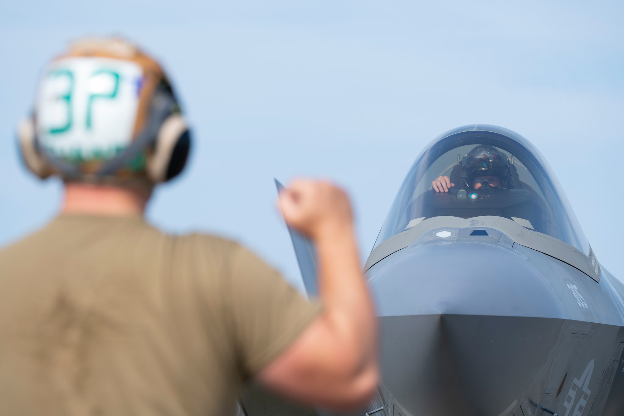 U.S. Navy Seaman Yevheniy Lyashenko, right, an Airframe Airman with the Strike Fighter Squadron (VFA) 86, signals to Lt. Austin “Chuck E Chaids” Douglas, VFA-86 F-35C pilot, during preflight checks during Red Flag-Alaska 25-2 at Eielson Air Force Base, Alaska, June 18, 2025.