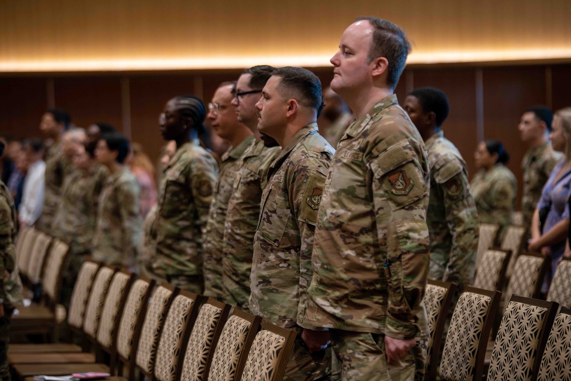 Military member stand at attention in the audience during a change of command ceremony