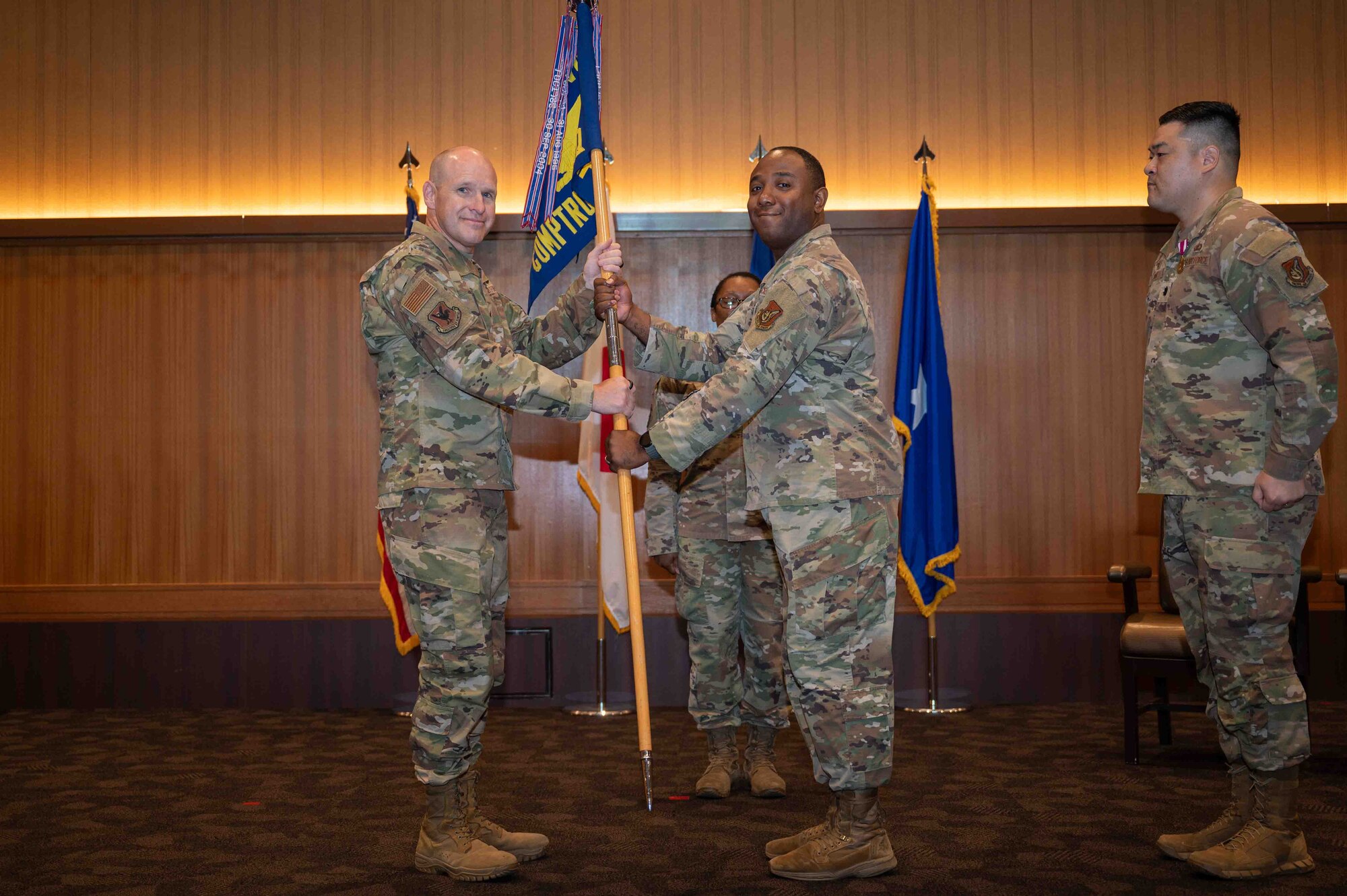 two Military members hold a flag together at a change of command ceremony