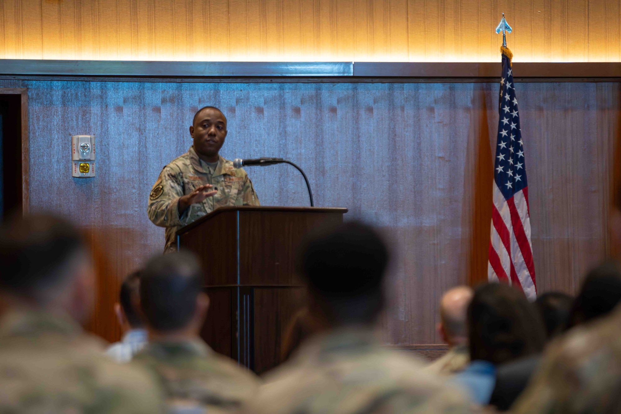Military member speaks at a podium in front of a crowd of people