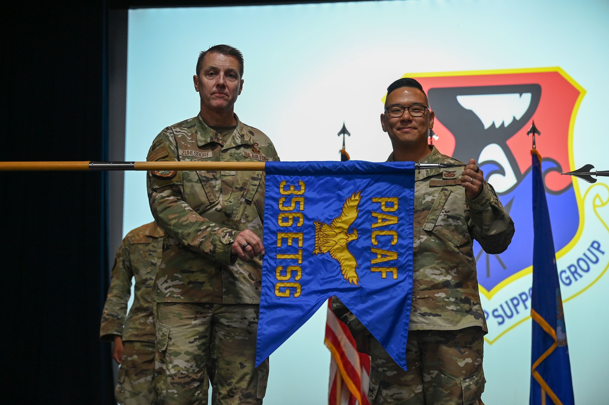 Two men unfurl a flag