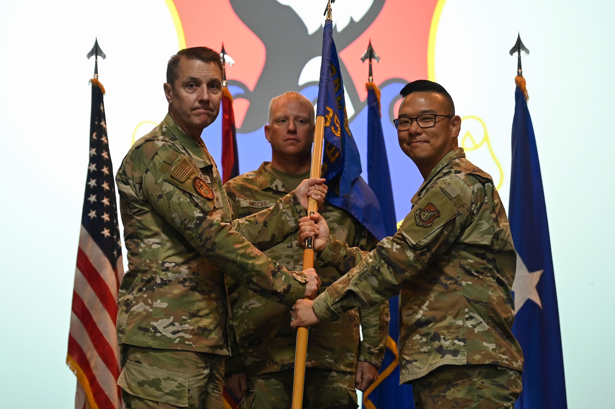 Two men pass a unit flag between them