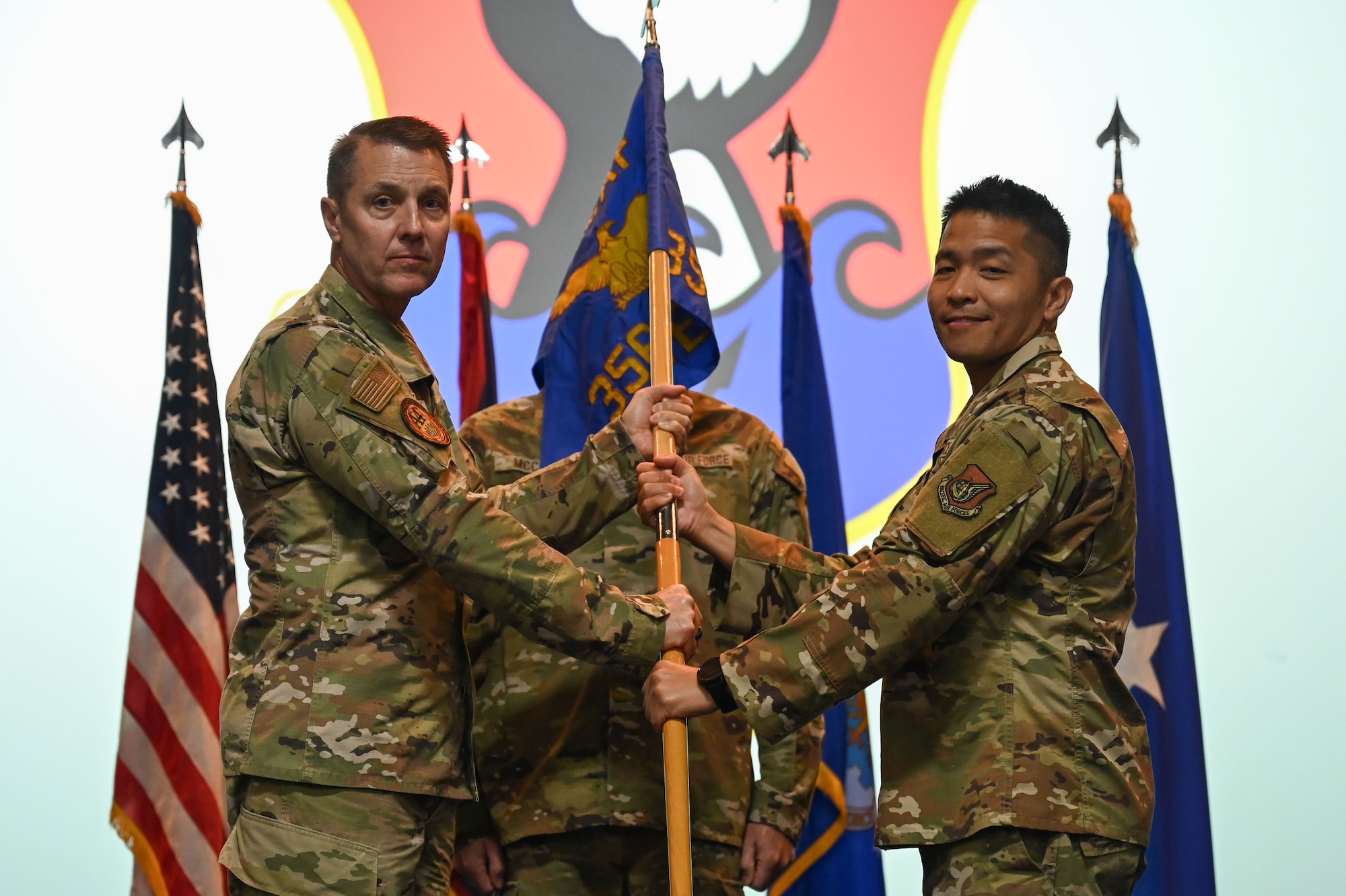 Two men pass a unit flag between them