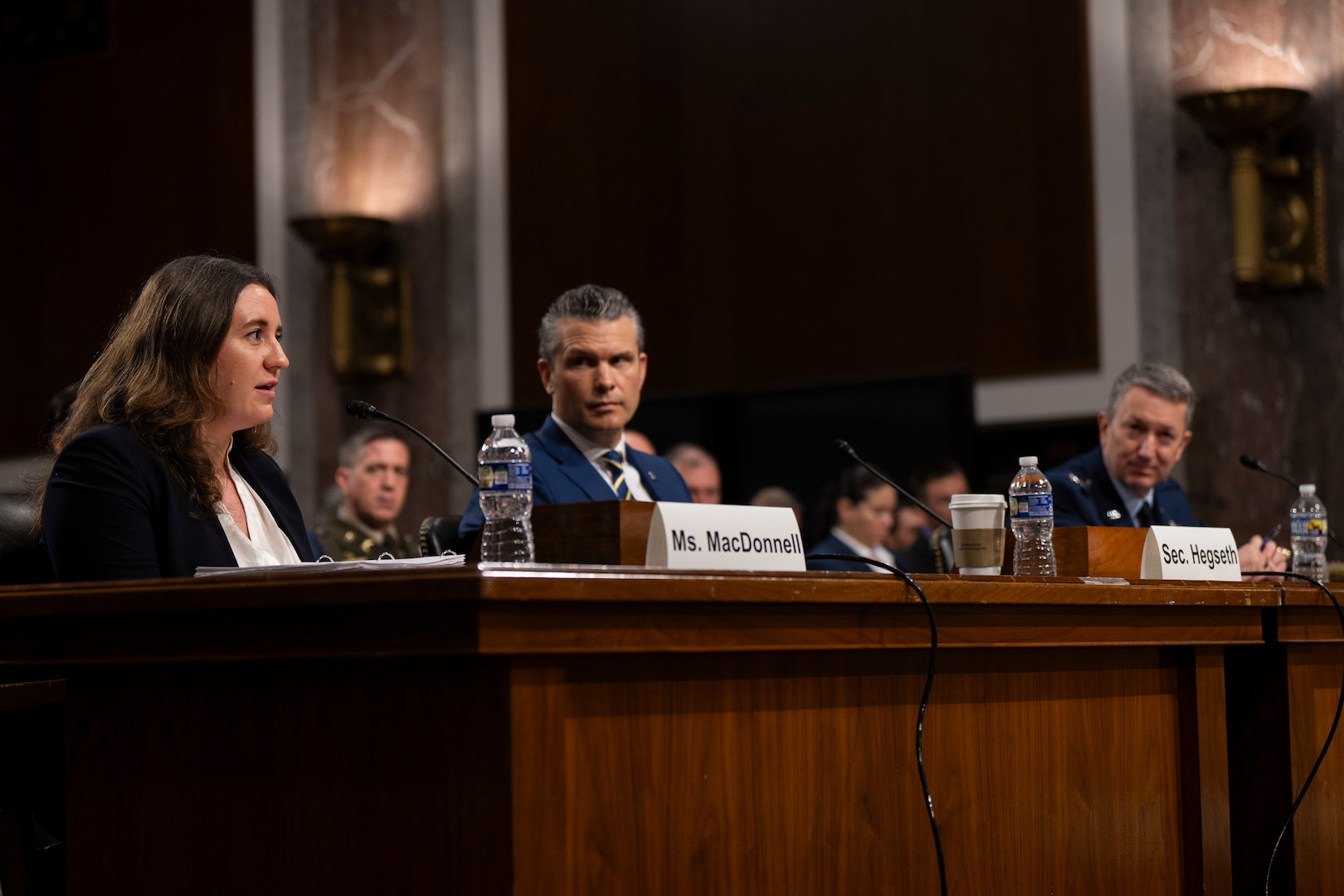 Three people sit at table during a hearing.