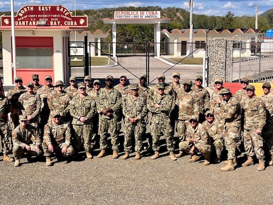 250115-N-FT324-2288. GUANTANAMO, Cuba (Jan. 15, 2025). Lt. Cmdr. Mikaela Pitcan, assigned to Joint Task Force Guantanamo, poses with her team on board Naval Base Guantanamo Bay, Cuba, during her deployment in support of overseas contingency operations. The image highlights the strength of joint operations and partnership between the U.S. Navy and U.S. Air Force. During her deployment Pitcan served as the sole psychologist and trusted mental health advisor to more than 1,500 Joint Task Force (JTF) warfighters across nine tenant commands. Mental resilience is key to deployability—strengthening a warfighter’s ability to perform, recover, and stay mission-ready in any environment.  (U.S. Navy Photo Released by Lt. Cmdr. Alicia Sacks)