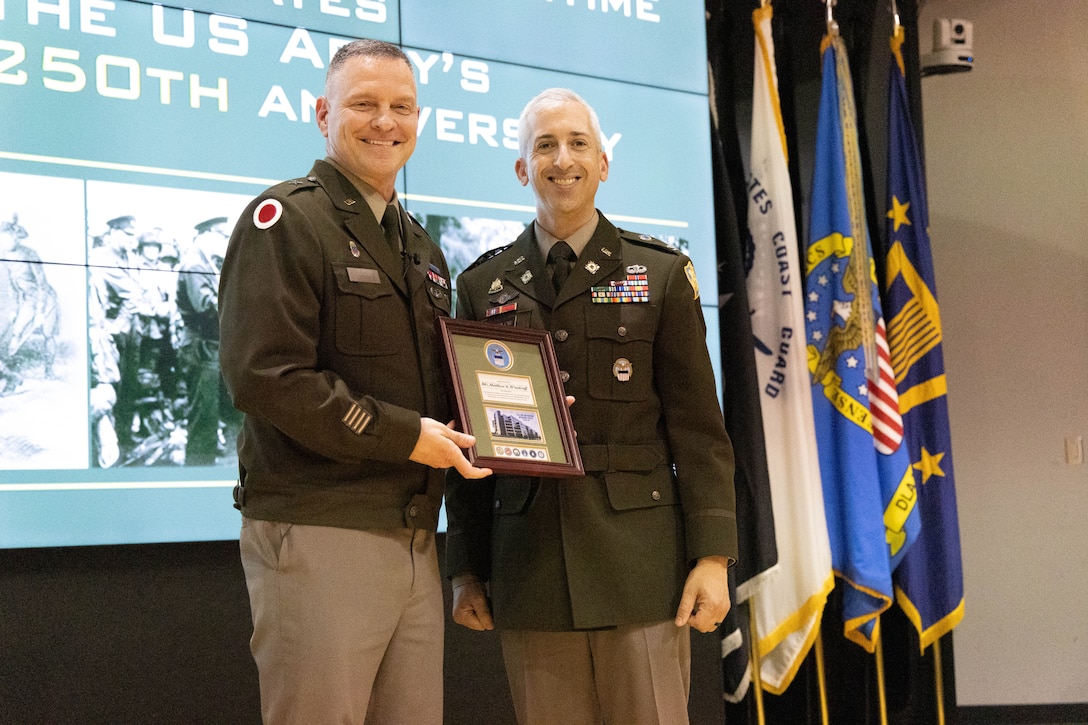 Two men in uniform hold a plaque.