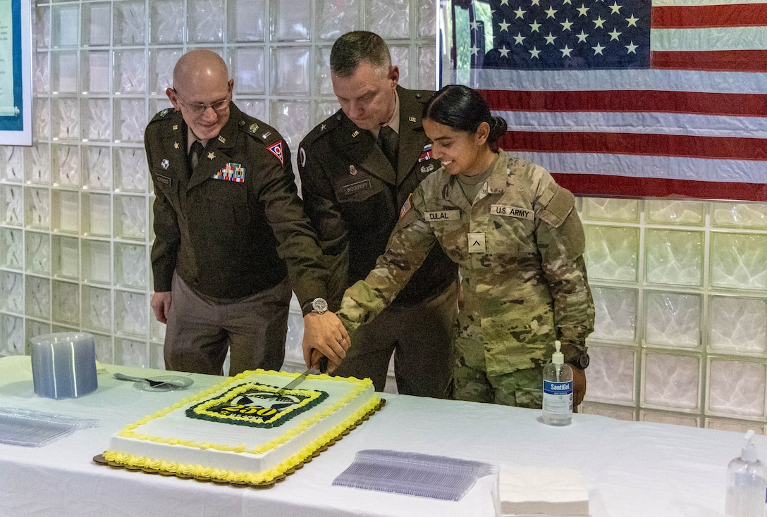 Three people in uniform cutting a cake.