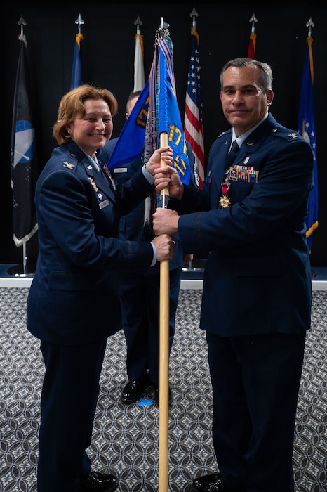 U.S. Air Force Col. Ian Rybchznski, outgoing 17th Medical Group commander, passes the guidon to Col. Angelina Maguinness, 17th Training Wing commander, relinquishing command during the change of command ceremony at the Powell Event Center, Goodfellow Air Force Base, Texas, June 18, 2025. Passing the guidon represents the transfer of leadership responsibilities to the next commander. (U.S. Air Force photo by Airman 1st Class Brian Lummus)