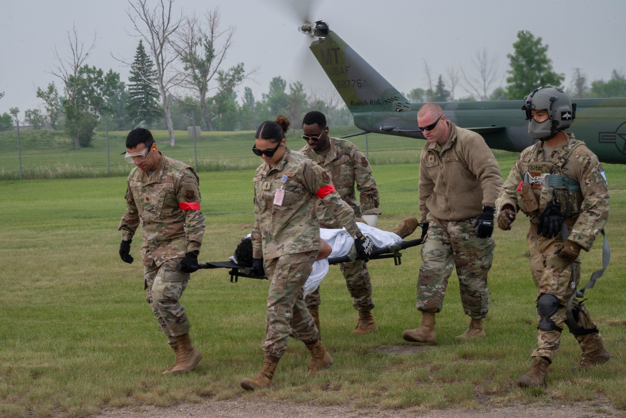 Airmen from the 5th Medical Group (5MDG)  carry a volunteer from a 54th Helicopter Squadron (54HS) UH-1N Iroquois helicopter on a stretcher at Minot Air Force Base, North Dakota, June 11, 2025. The 54HS participated in the training exercise to strengthen cross-functional teamwork between the 5MDG and flying units during high impact training beyond routine clinic operations. (U.S. Air Force photo by Airman 1st Class Wesley Davies)