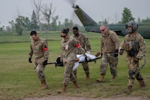 Airmen from the 5th Medical Group (5MDG)  carry a volunteer from a 54th Helicopter Squadron (54HS) UH-1N Iroquois helicopter on a stretcher at Minot Air Force Base, North Dakota, June 11, 2025. The 54HS participated in the training exercise to strengthen cross-functional teamwork between the 5MDG and flying units during high impact training beyond routine clinic operations. (U.S. Air Force photo by Airman 1st Class Wesley Davies)