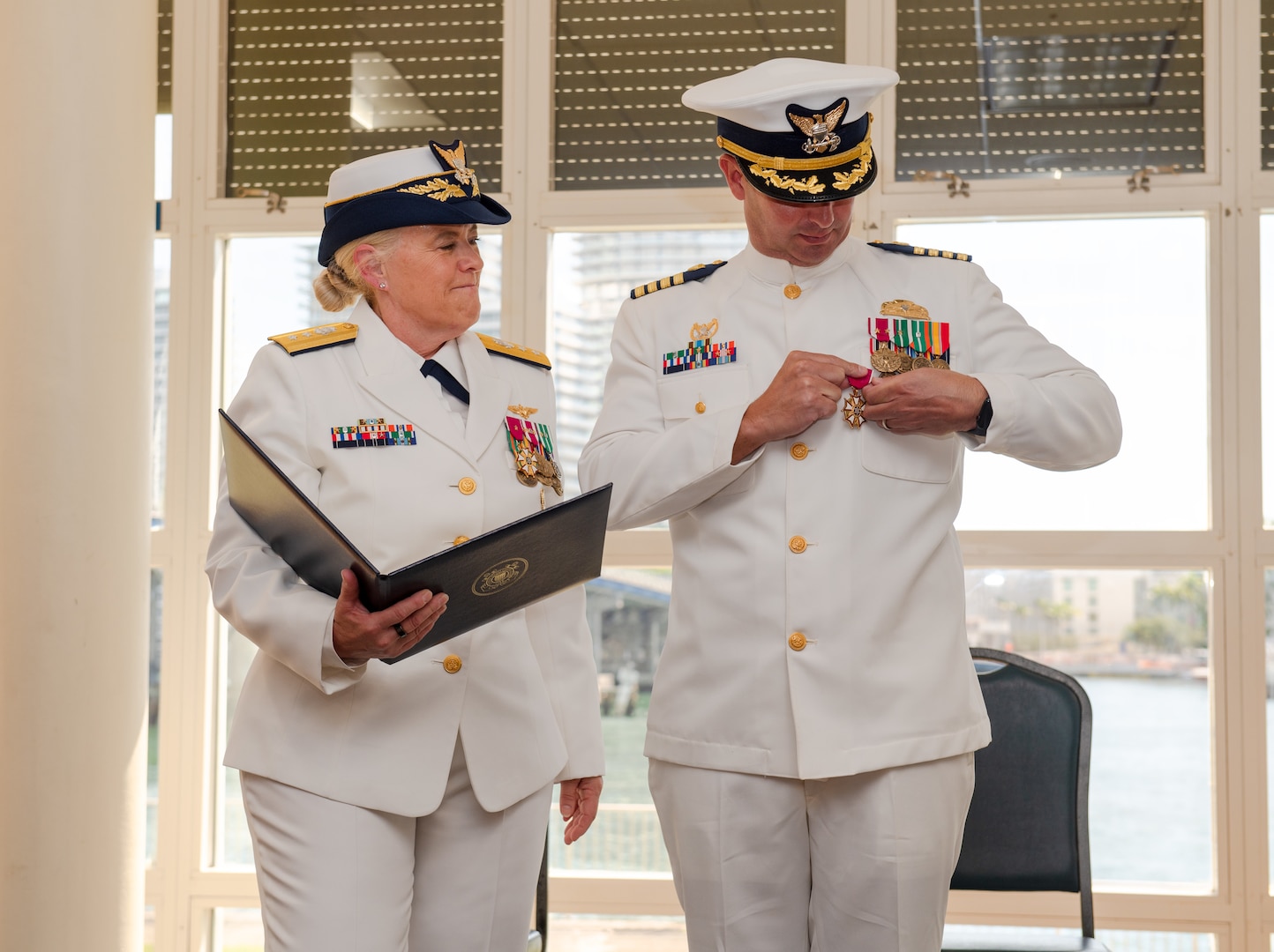 Military member adds medal to uniform at a ceremony