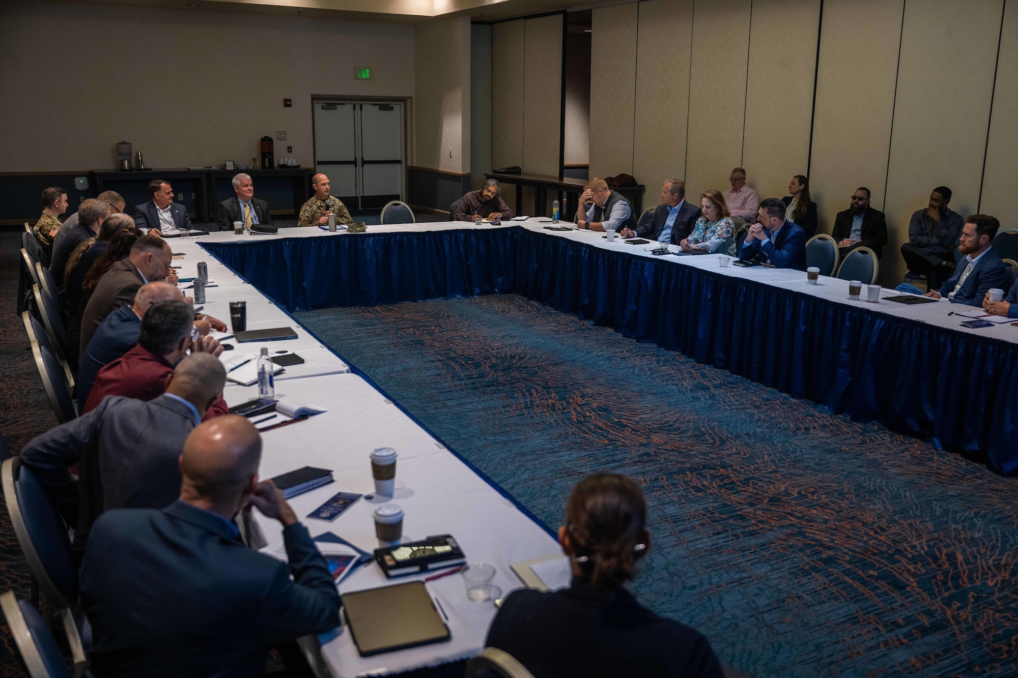 A group of people sitting at tables exchange ideas in a large room.