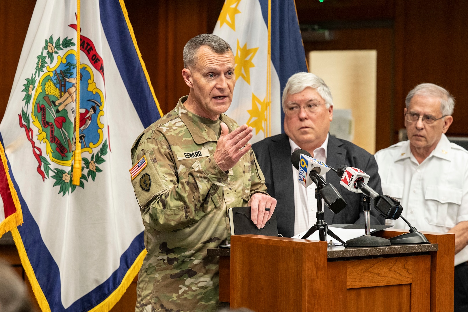 photos of the adjutant general in uniform talking at a press conference with the governor, visiting people, sitting around a conference table.
